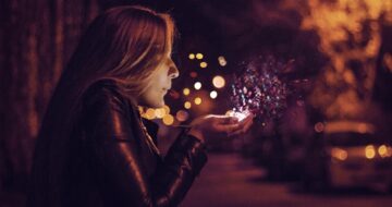 woman blowing glitter from hand