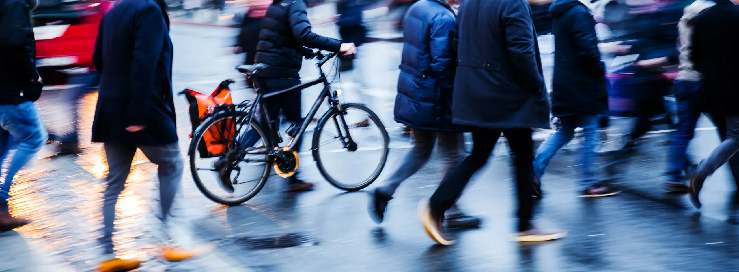 people and bicycle crossing a city street at dusk