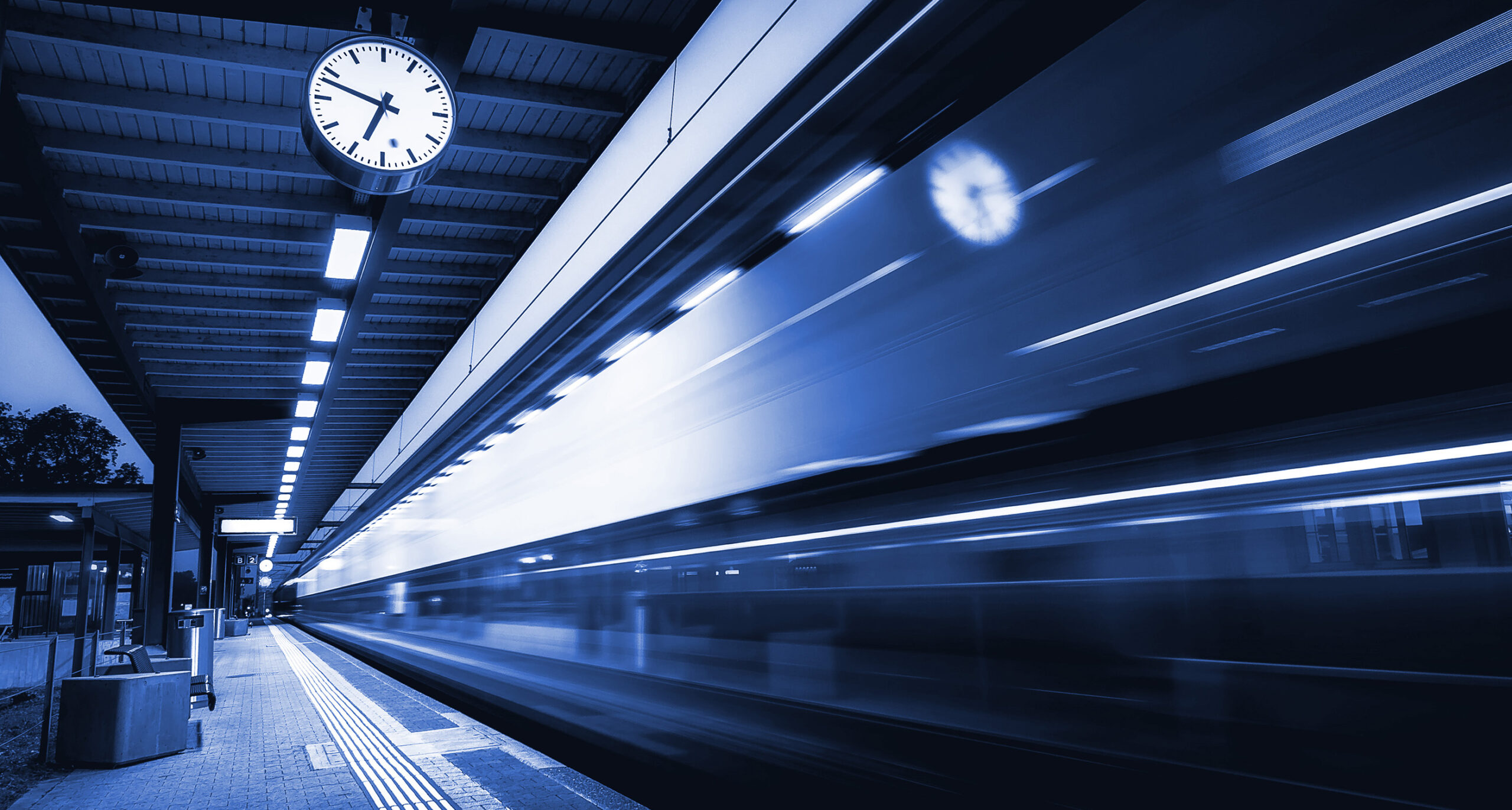 A blue tinted high speed rail station. Train speeding by in a blur. Photo by Jan Huber, Unsplash